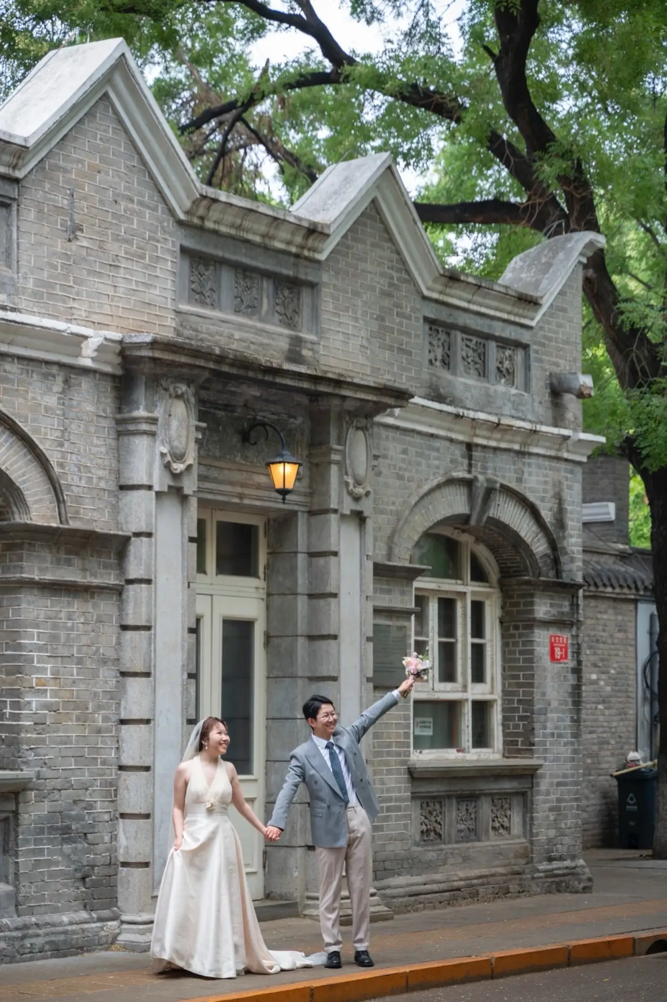 Couple posing for wedding photos outside preserved grey-brick buildings in Xijiao Minxiang, a historic hutong known for its former financial district architecture in Beijing.