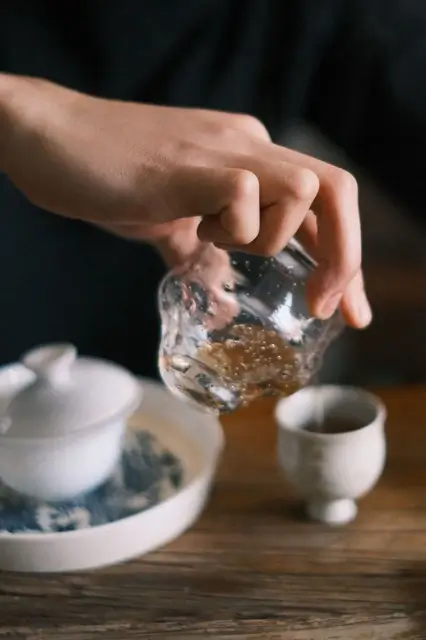 Close-up of tea being poured from a glass pitcher into a small cup during a Chinese gongfu tea sessi