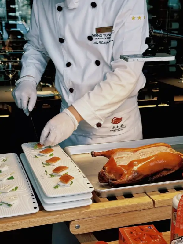 Chef carving Peking duck into thin slices at the restaurant counter