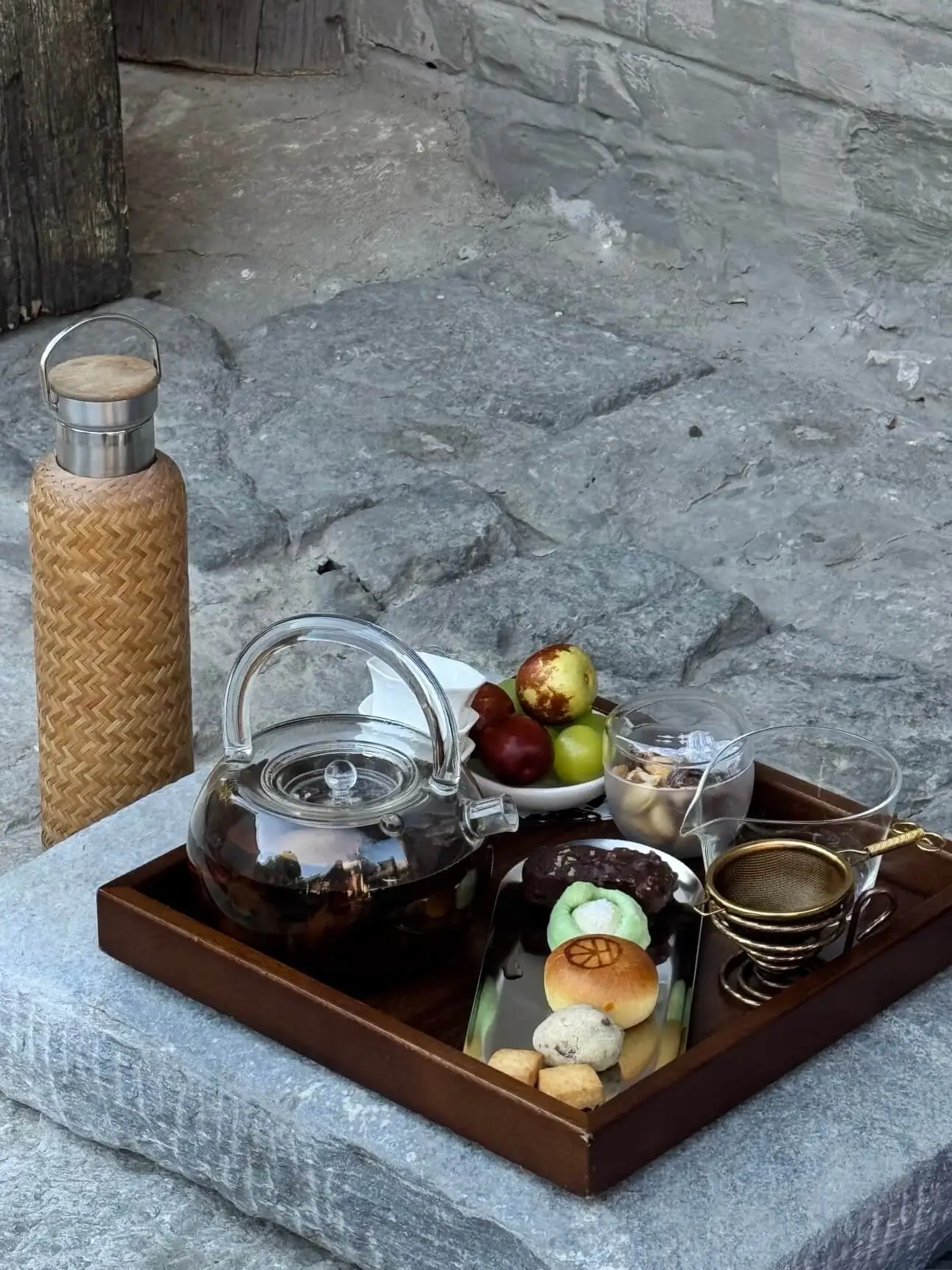 Tea set with glass teapot, snacks, and fruit served on a tray in a temple teahouse setting in Beijin