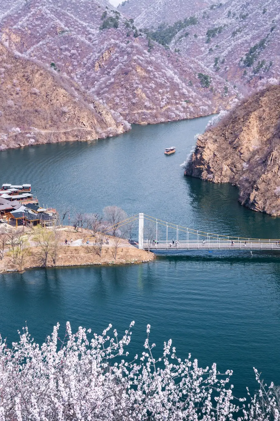 Huanghuacheng Water Great Wall lake view with boat and suspension bridge, showcasing a peaceful and less crowded Beijing Great Wall experience