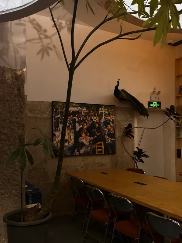 Art lined walls and wooden table with greenery at Metal Hands Café Dongsi