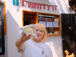 Traveler holding a handmade baozi in front of a traditional Beijing snack shop.