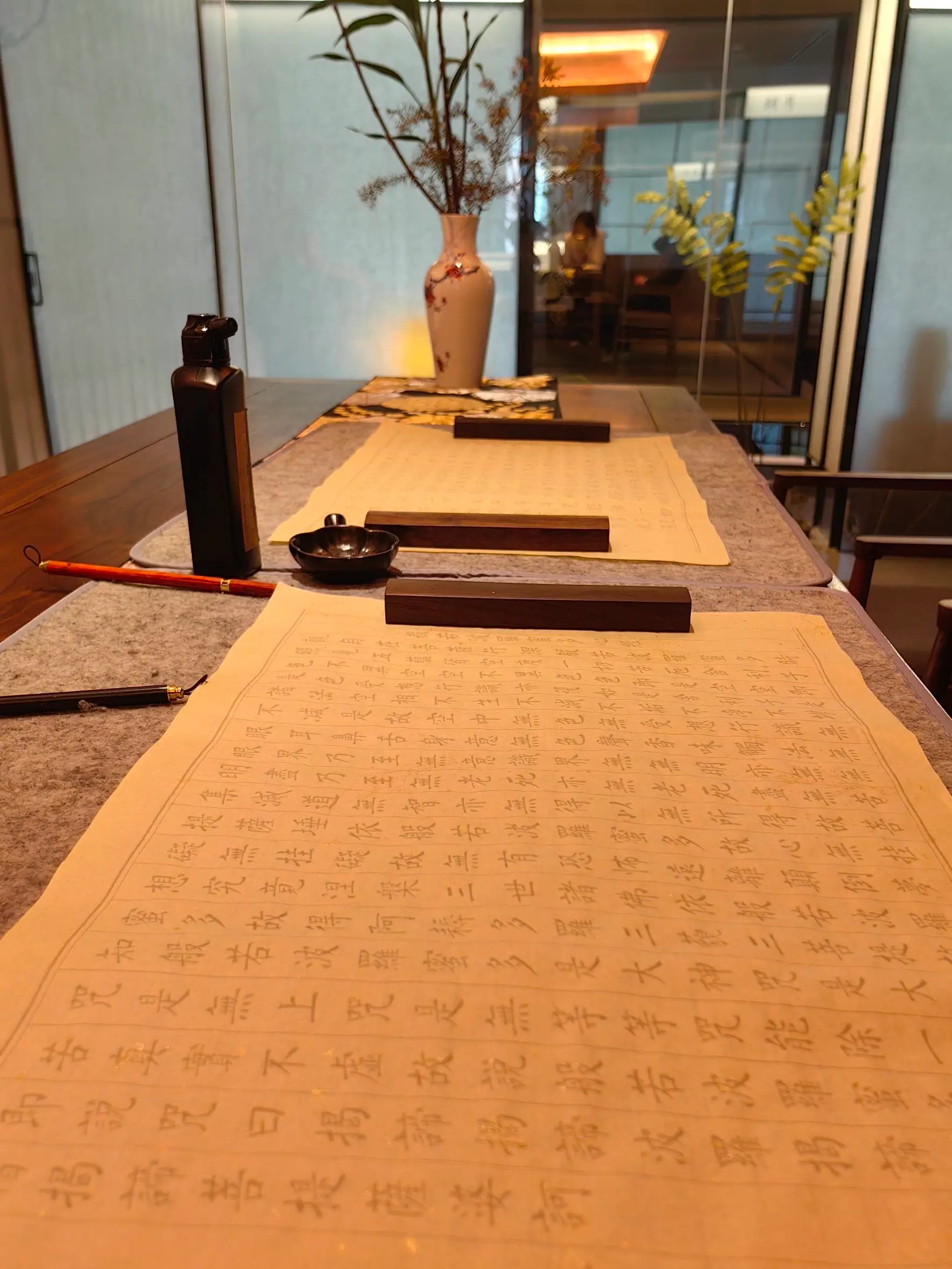 Traditional Buddhist scriptures setup with brush, ink, and scripture copying on a long table in a qu