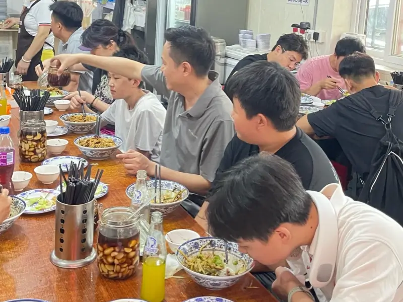 diners enjoying bowls of zhajiangmian inside the shop