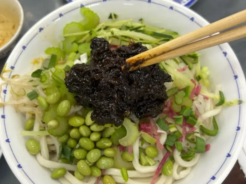 bowl of zhajiangmian topped with soybean paste and vegetables