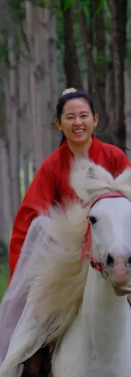 Smiling woman in red riding outfit on a white horse during a Beijing countryside horseback riding tour.