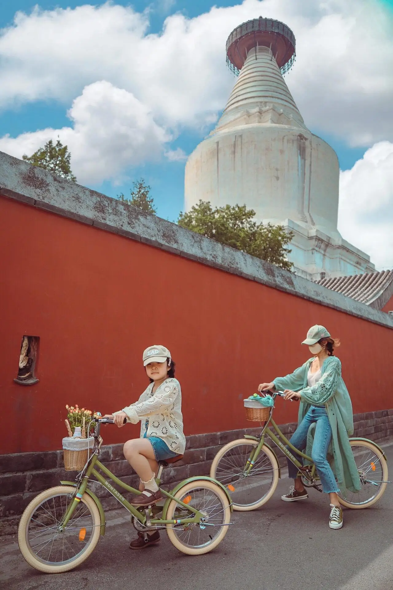 Parent and child cycling through Beijing hutongs near a historic temple, enjoying a relaxed city ride