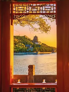 A view of the Tower of Buddhist Incense (Foxiang Ge) on Longevity Hill and Kunming Lake, framed beautifully by traditional Chinese wooden window lattice, with warm golden light, as part of the BiteEscape private Great Wall tour