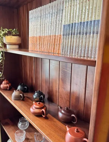 Row of traditional clay teapots displayed on a wooden shelf inside a classic Chinese teahouse