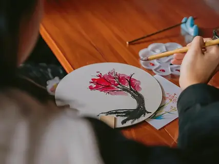 Painting bamboo or orchids on a traditional Chinese silk round fan.
