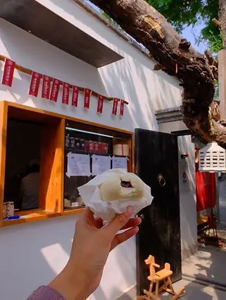 Freshly steamed baozi held outside a local hutong bun shop in Beijing, part of a Lama Temple and baozi food experience.