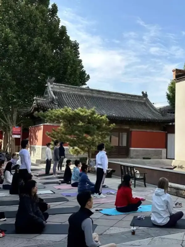 Group yoga class held outdoors in the courtyard at Temple Dongjingyuan