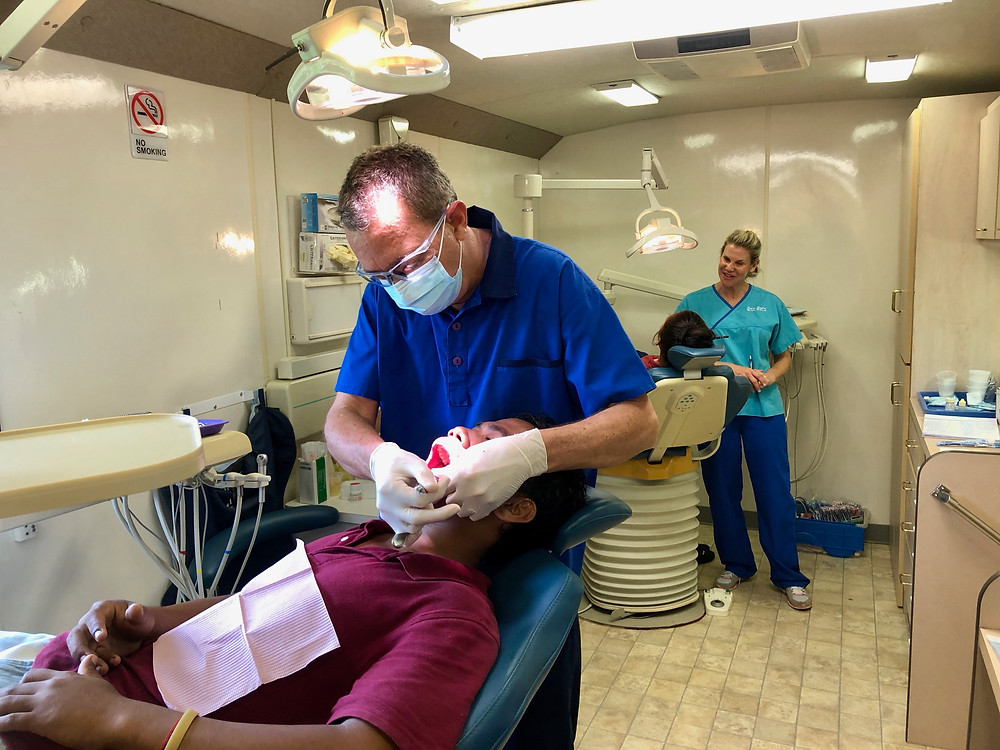 Dr. Gearing at work (front) with Nicole Gearing providing dental health education