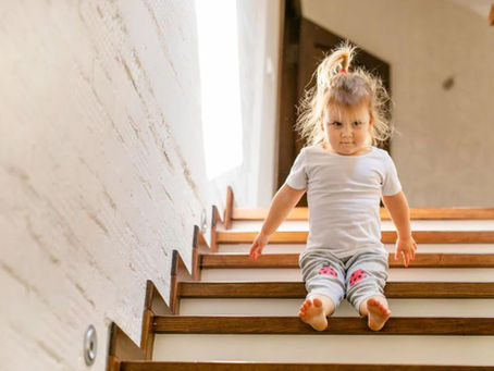 Dieťa sediace na drevených schodoch v interiéri domu – bezpečné schody na mieru pre rodinu