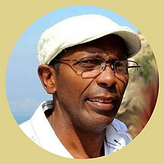 Sérgio Jitu aparece de rosto. Pele negra, óculos, boina e camisa branca.