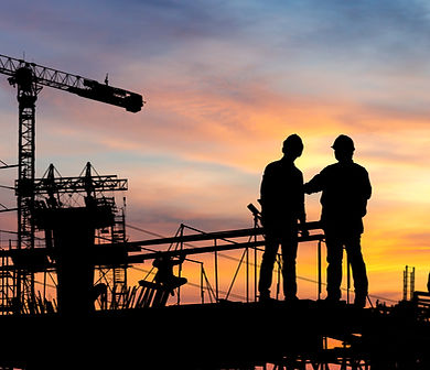 Two construction workers at a site with a crane at sunset