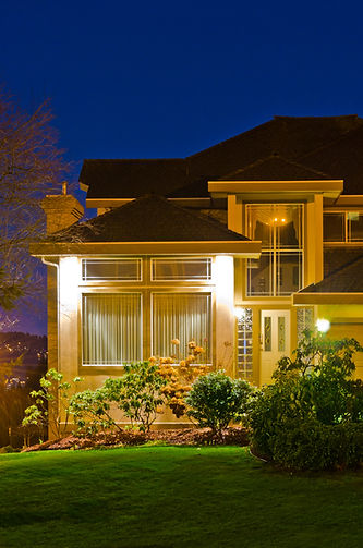 Beautiful house exterior at night with bright outdoor lighting.