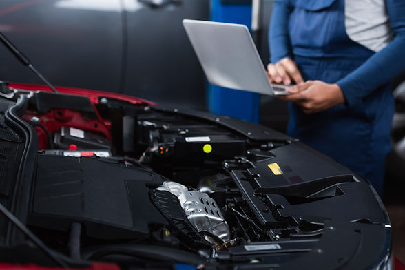 Mechanic performing car engine diagnostic with laptop