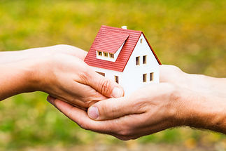 Hands holding a miniature house model outdoors