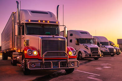 Several semi-trucks parked at sunset