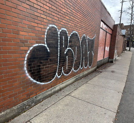 Black graffiti tag with white outline on a brick wall