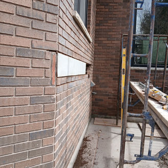 Brick wall repair with scaffolding and level.