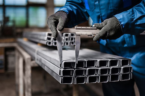 Worker measuring structural steel beams with a caliper.
