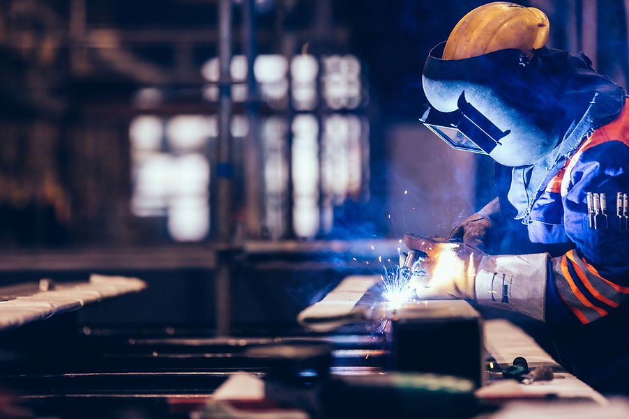 Welder in protective gear welding metal in a factory