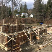 Wooden forms awaiting concrete, construction site, homes in the background.