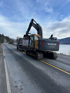 Volvo excavator being transported on a flatbed truck by water