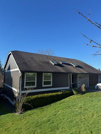 Single-story gray house, dark roof, three skylights, green lawn.