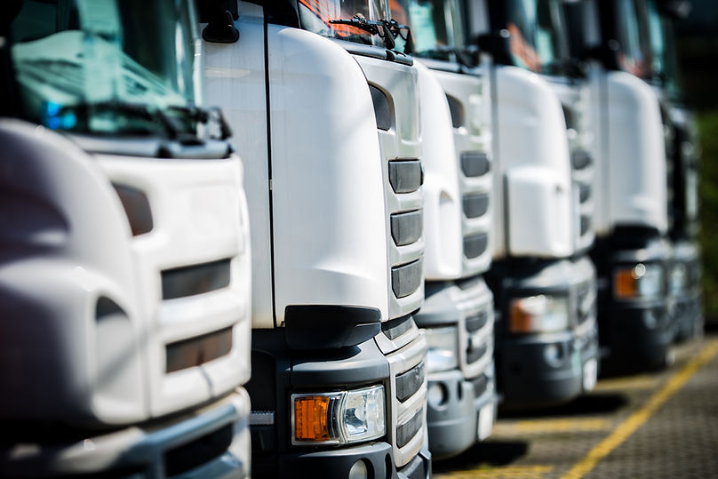 Row of white semi-trucks parked in a parking lot.