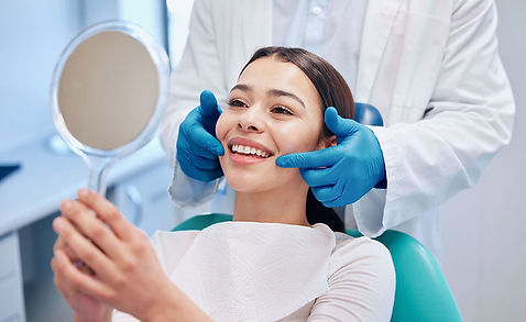 Patient smiling in a mirror after restorative dentistry.