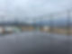Black chain-link fence enclosing wet asphalt court, mountains in background.