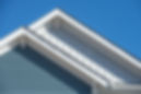 Modern house gables with blue and white siding, clear sky.