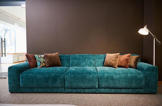 Clean teal fabric sofa with brown throw pillows.