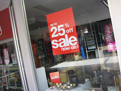 Red 'up to 25% off SALE now on!' sign in store window