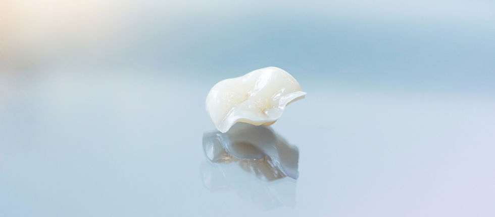 Single white ceramic dental restoration sits on a bright reflective surface.