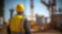 Engineer in yellow hard hat observing large construction project with cranes.
