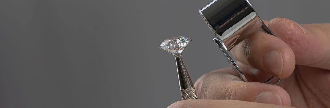 Diamond being inspected with tweezers and a loupe