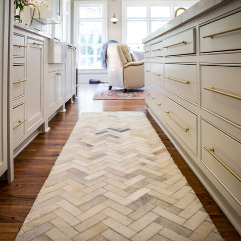 Kitchen with island, white cabinets, and patterned rug