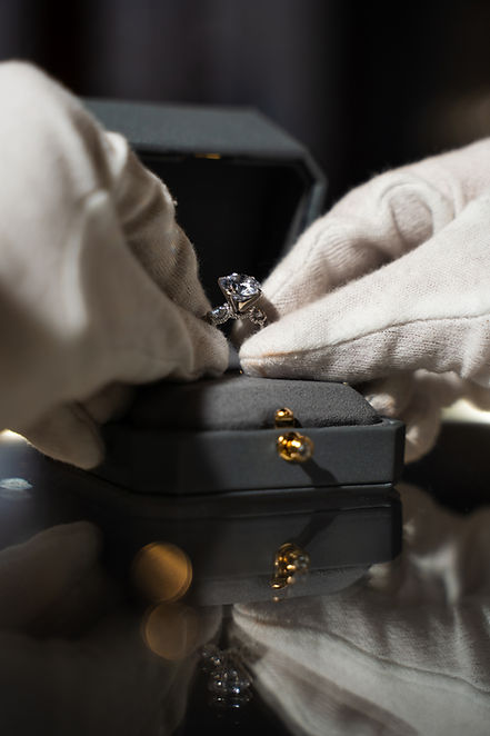 White-gloved hands placing engagement ring in box
