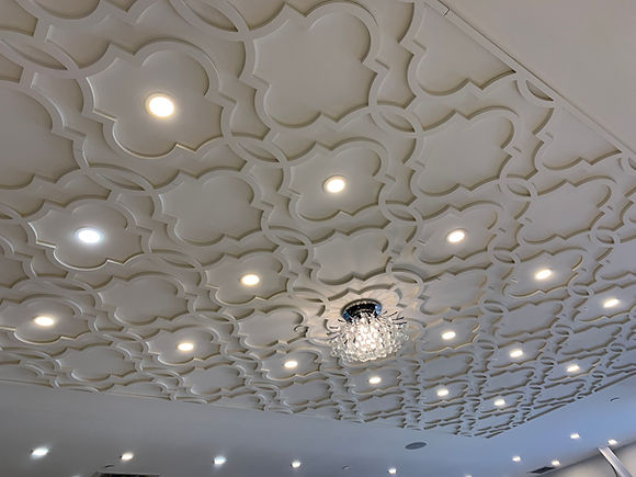 Ornate geometric ceiling with recessed lights and chandelier