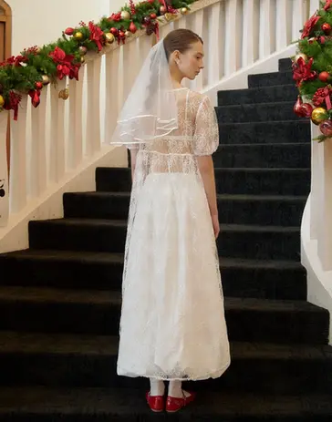 Bride in white dress, veil, on black stairs with Christmas garland.