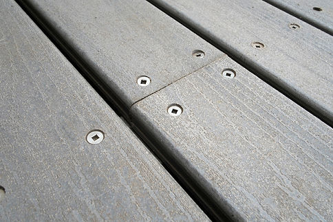 Close-up of grey composite decking with square head screws.