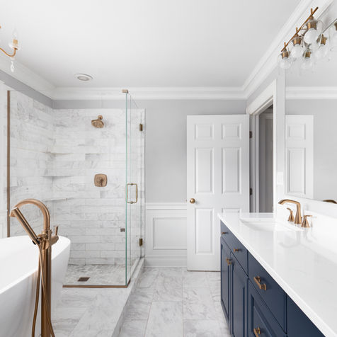 Elegant bathroom with bronze fixtures, freestanding tub, glass shower, and blue vanity