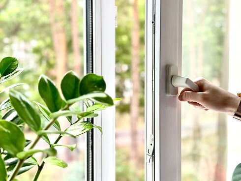 Hand opening a white uPVC window overlooking a forest.