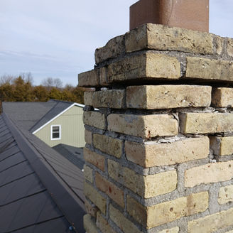 Deteriorated brick chimney needing repointing services.