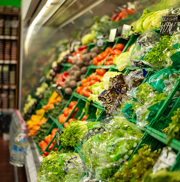 Fresh produce displayed in commercial refrigeration units.